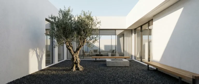 Vista panorámica de un patio interior minimalista con árbol escultural y grandes ventanales que conectan con el salón.