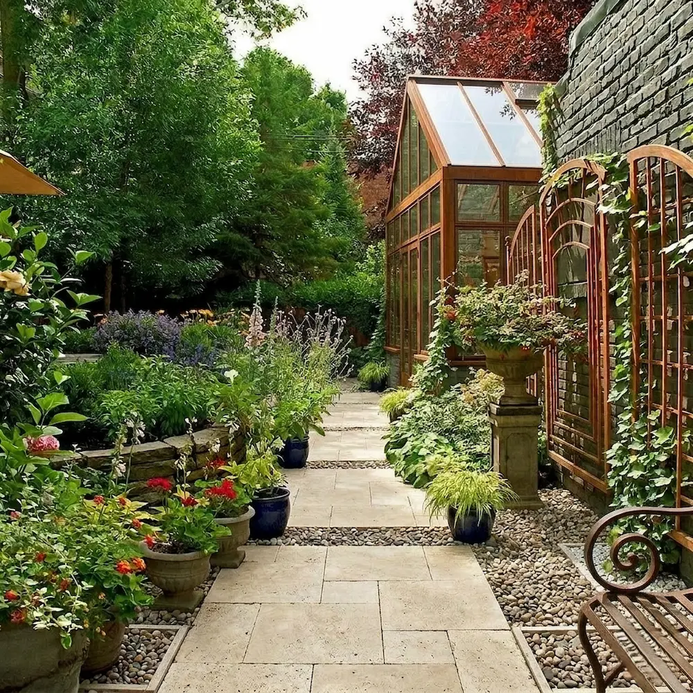 rincón jardín estilo ingles con invernadero y grandes árboles al fondo