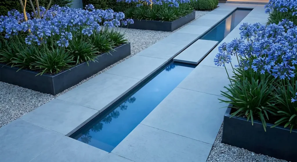 El azul del agua y el azul de la flor se potencian mutuamente creando una atmósfera abierta, fresca y muy relajante. Las macetas de agapantos azules en primer plano enmarcan la escena minimalista.