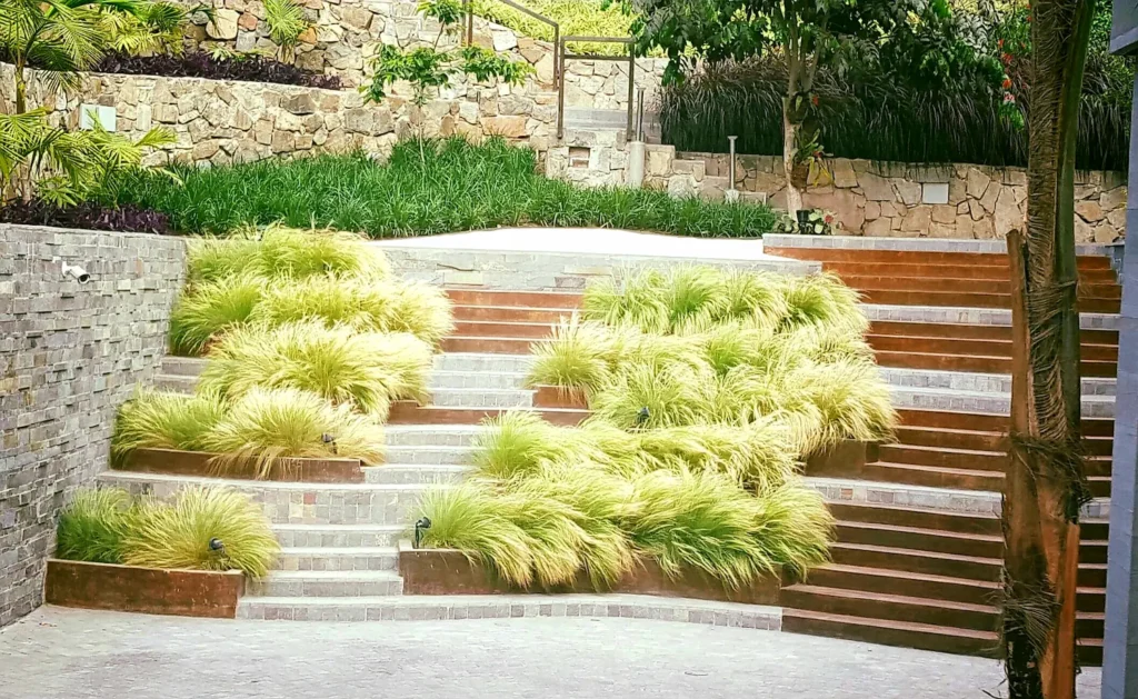 Terraced stone garden with multiple steps and clusters of ornamental grasses in a landscaped courtyard