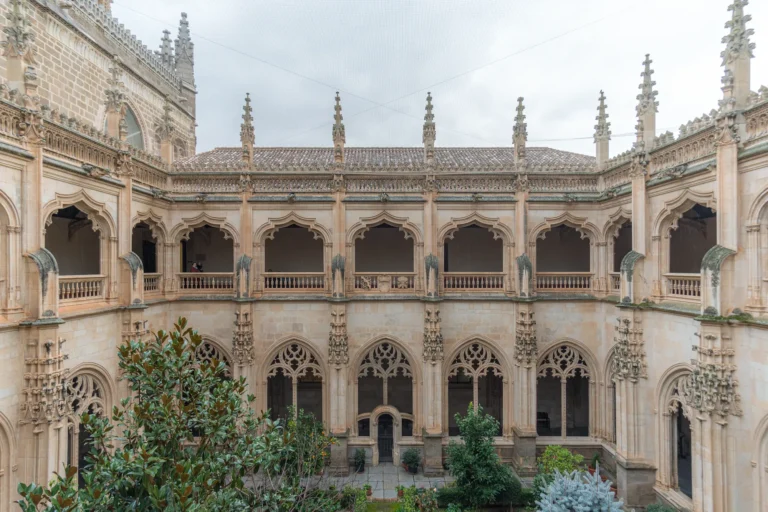 Perspectiva general del claustro del Monasterio de San Juan de los Reyes en Toledo, mostrando la transición orgánica entre la arquitectura gótica y la composición vegetal.